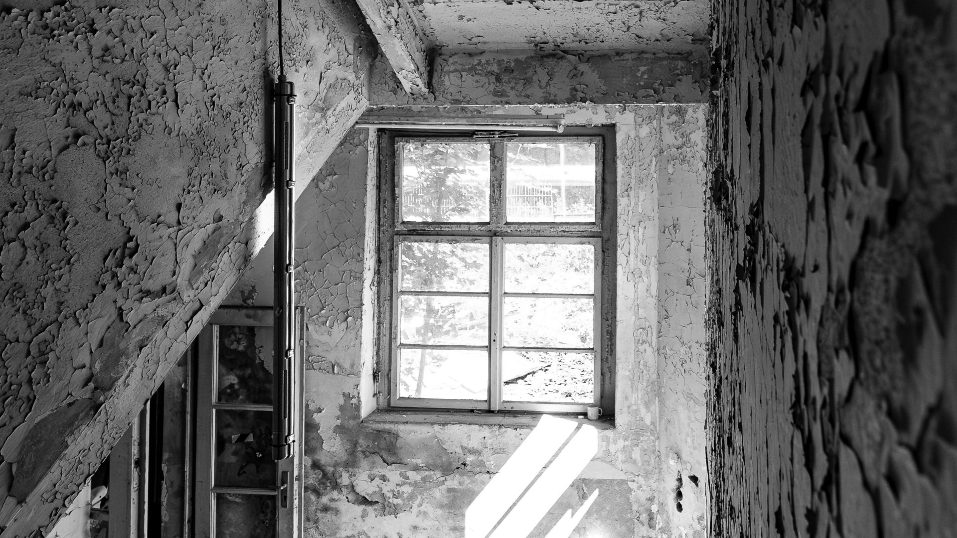 Sunlight streaming through an old window illuminates an abandoned stairwell in Chemnitz.