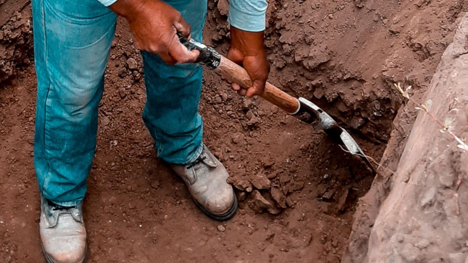 A construction worker in safety gear digs at a site in Lambayeque, Perú, showcasing manual labor and construction processes.