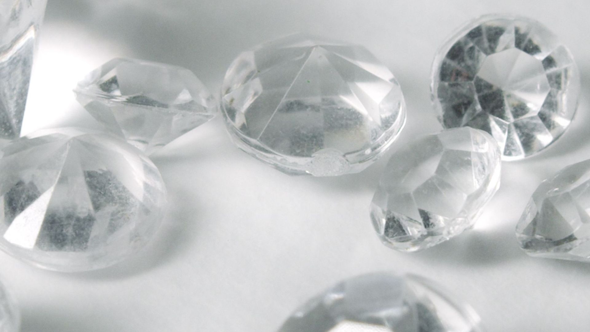 A close-up of various clear-cut gemstones on a white surface, showcasing their sparkle and clarity.