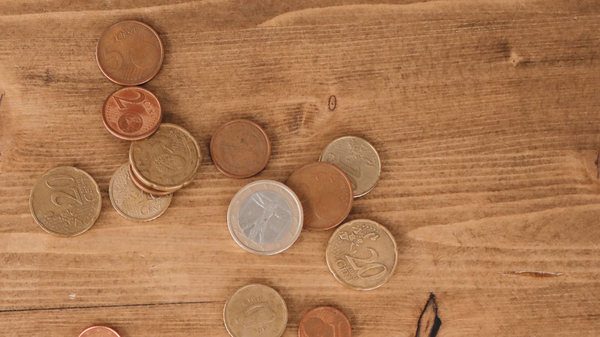 Flat lay of tax forms and scattered coins on a wooden table, illustrating finance and taxation concepts.