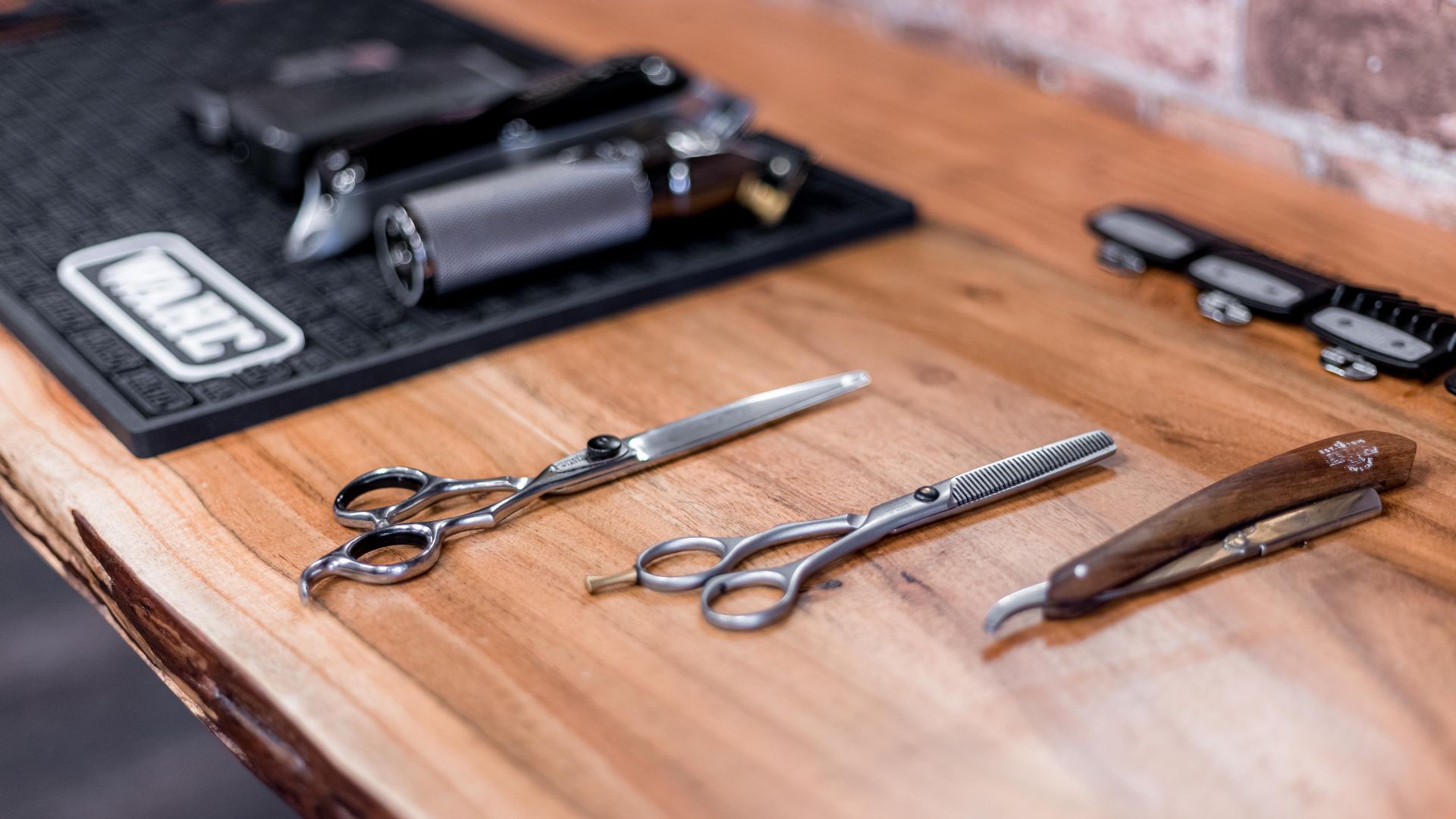 High-quality barber tools arranged on a rustic wooden table in a modern salon.