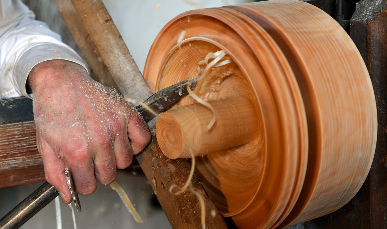 11 December 2019, Saxony, Seiffen: Wooden toy maker and tire lathe operator Christian Werner works on the lathe in his workshop in Seiffen. Special turning tools are used to turn the profile of a figure into the wet wood. Only after splitting does the silhouette of the figure reveal itself. The blanks are later carved, glued and painted. The technology in the small workshop with its six employees is still the same as it was 200 years ago when the turning of tyres in the Erzgebirge mountains was started. The craft in Seiffen is now unique in the world and is only practiced by a handful of wooden toy makers.