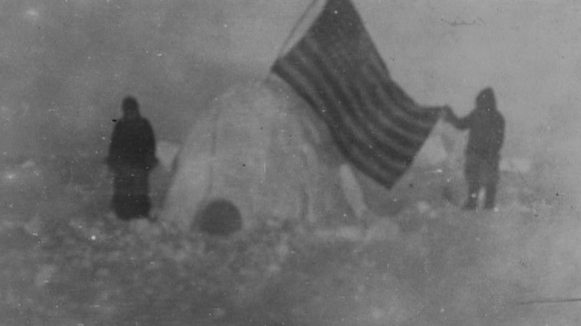 A photo of Frederick Cook's 1909 arctic expedition. Cook alleged that this photo was take near the North Pole. From that page: TITLE:  Two members of Frederick Cook's expedition, with U.S. flag stuck in igloo, at expedition camp site, North Pole CALL NUMB
