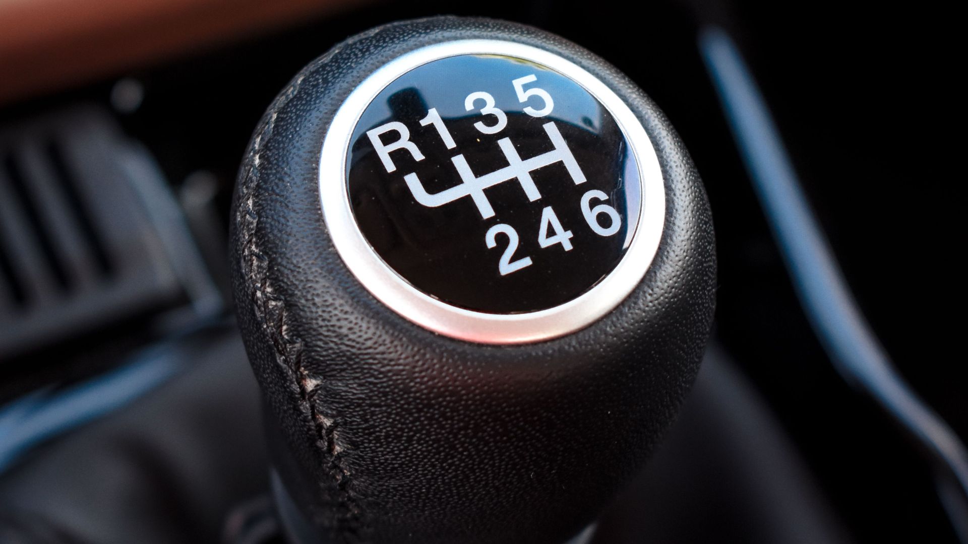 Detailed view of a manual gear shift knob in a car interior showcasing gear positions.