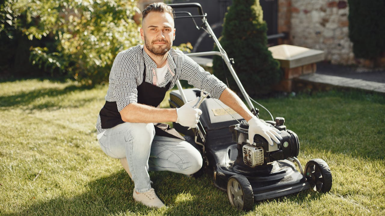 Man Sitting beside a Lawn Mower