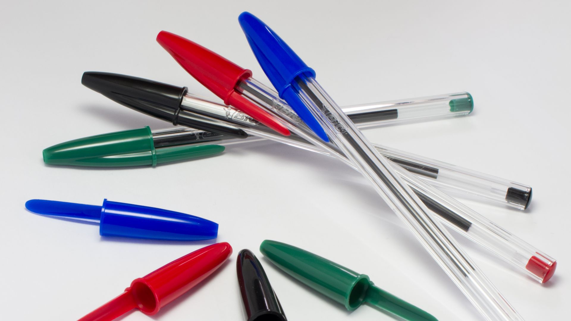 Four blue, red, black and green BIC pens and four pen caps.