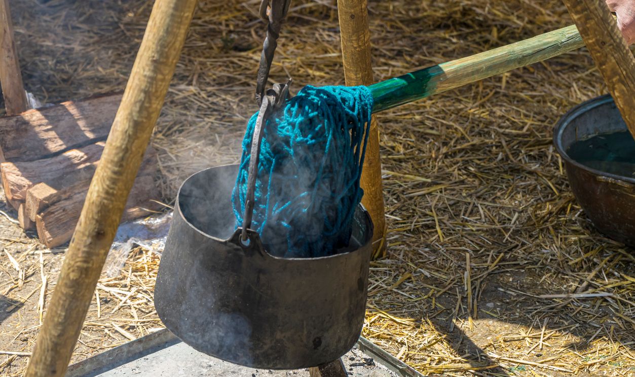 Tradition handmade dyeing of fabrics and wool in a cauldron with colored dyes in a medieval fair in Spain