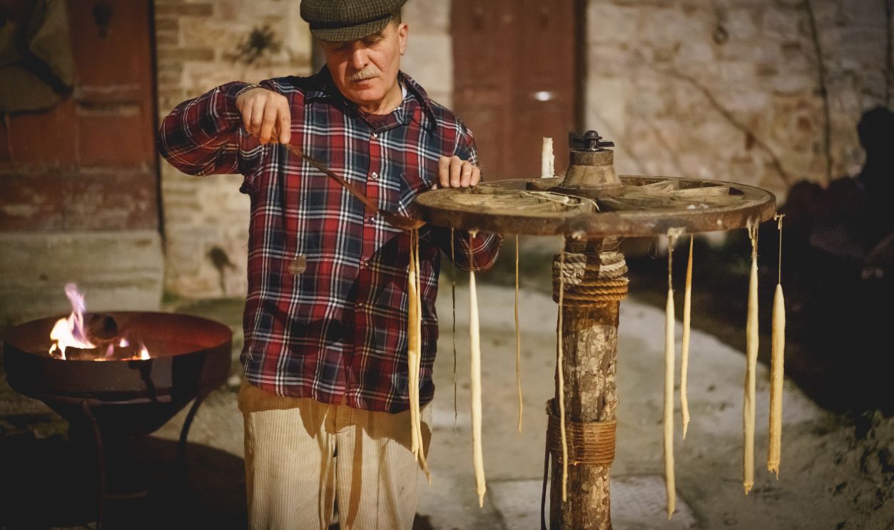 Foligno, Italy - January 2018. A man manufacturing candles with a traditional method during a living Christmas Nativity scene reenactment. 
