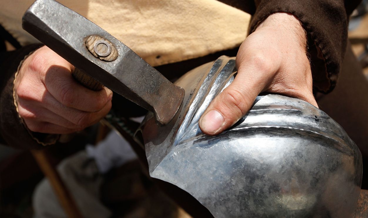 ST. WENDEL, GERMANY - SEPTEMBER 01: A man dressed in clothes of the Middle Ages works on a knight's armour during the Knights' Tournament on September 1, 2012 in St. Wendel, Germany. The event marks the 500th anniversary of a visit by Emperor Maximilian I to St. Wendel. In contrast to other historical reenactments, St. Wendel organizers claim they have brought dedicated and highly-trained enthusiasts from across the globe and that all clothing, weapons, tools and other accessories have been made with great attention to detail and historical accuracy. The day's program included real jousts, authentic music, a display of coats of arms, demonstrations of Middle Ages artillery use and sword fighting and a full charge by opposing cavalry.