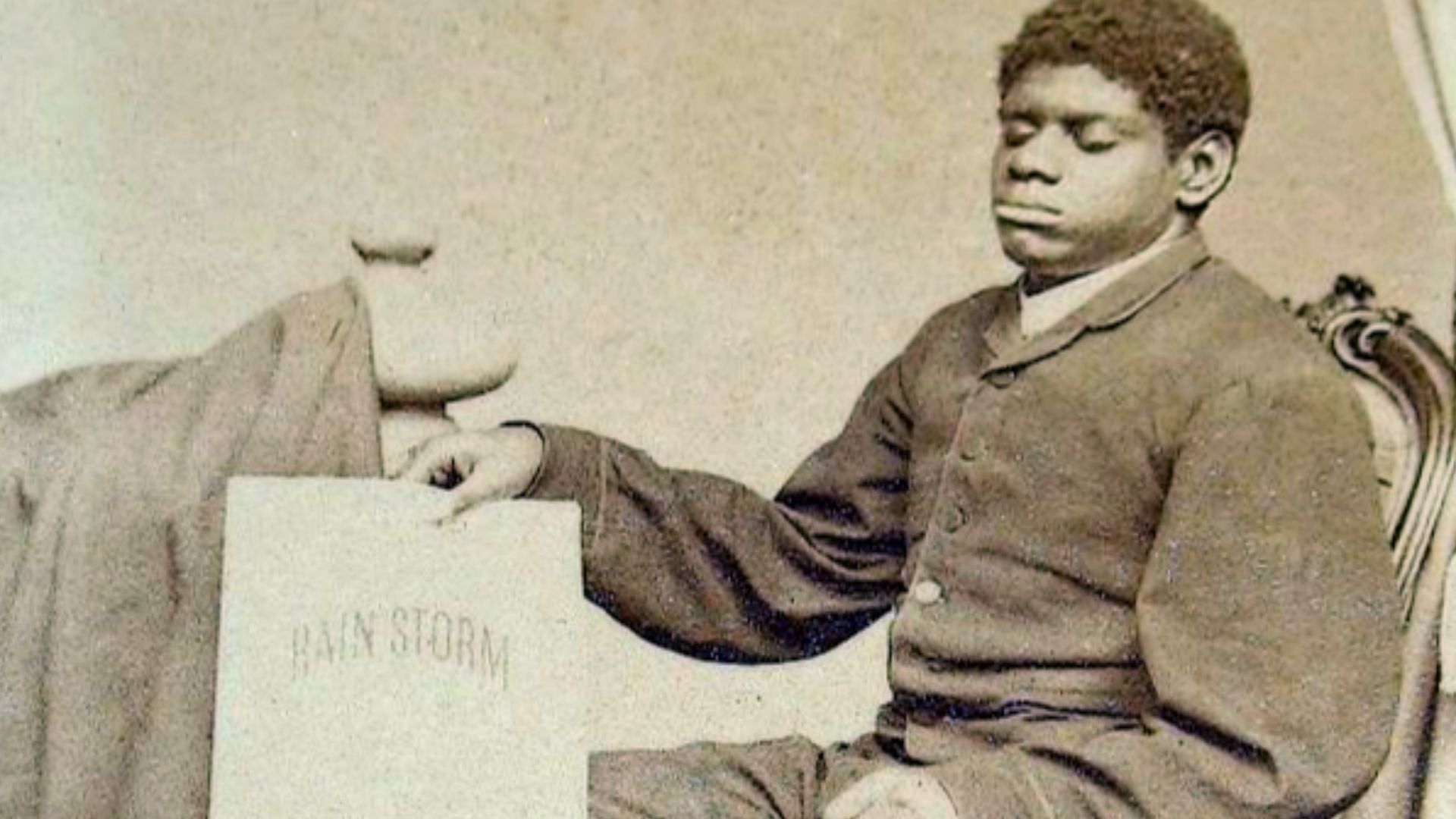 Blind Tom Wiggins holding a copy of his first musical composition, The Rain Storm.