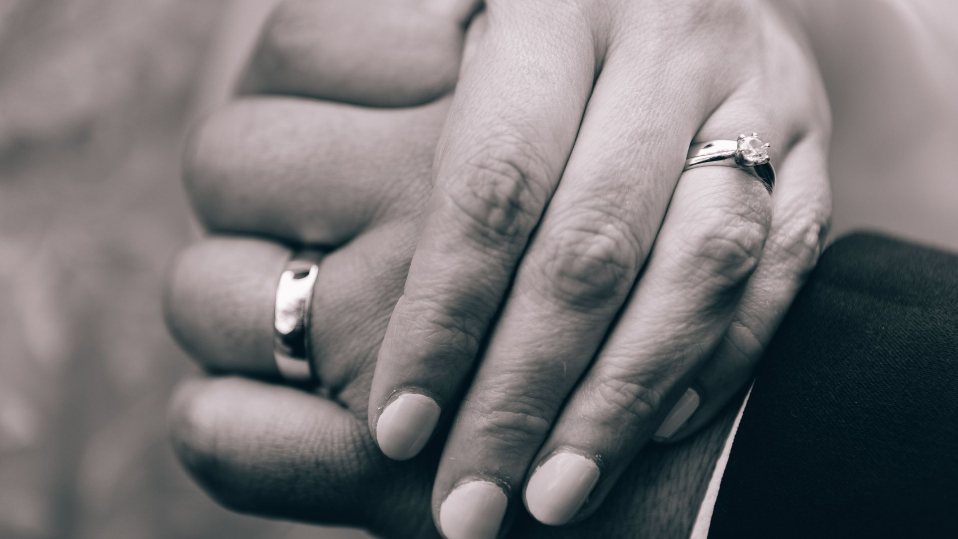 Close-up of bride and groom's hands showcasing wedding rings in an intimate embrace.