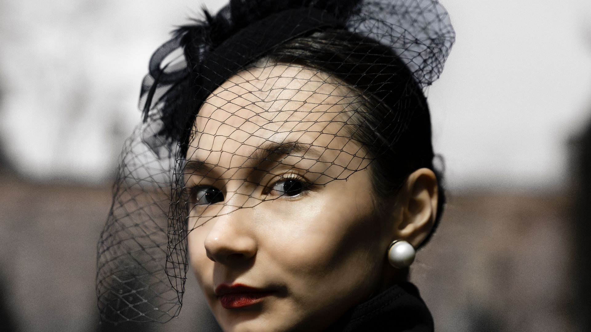 Portrait of an elegant woman in vintage black attire with a stylish hat, outdoors.
