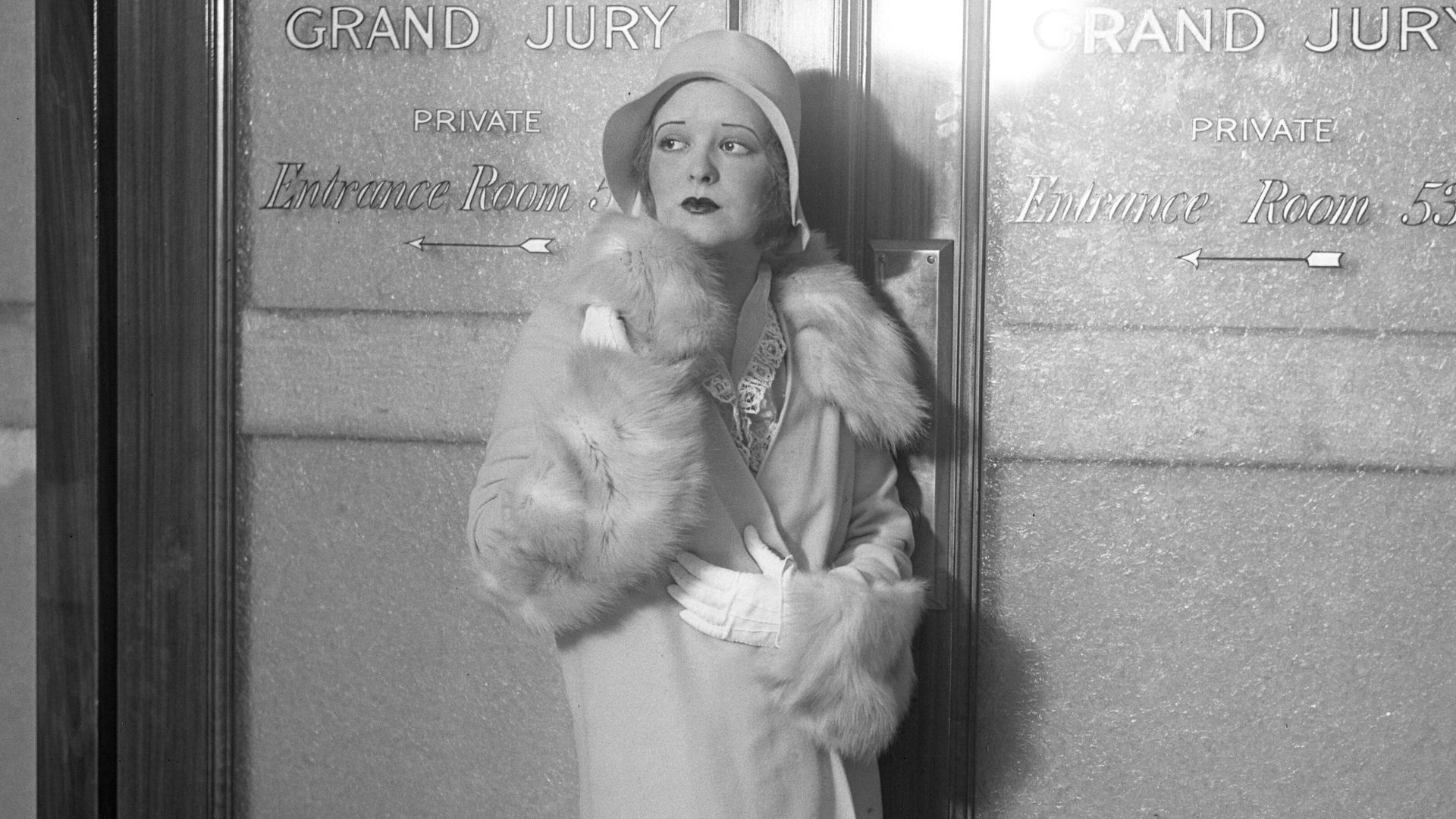 Motion picture actress Clara Bow posing in front of Los Angeles Grand Jury room doors