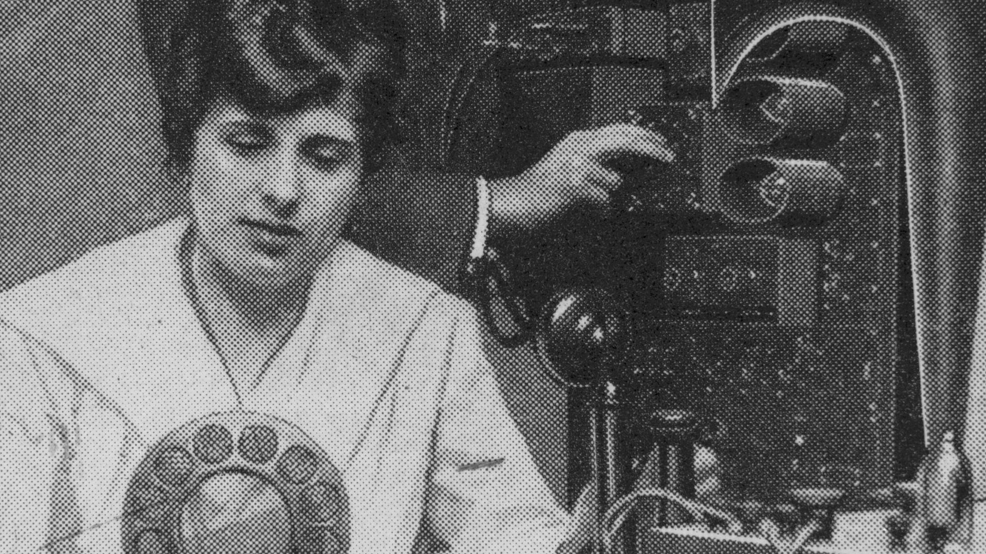Copy of a clipping with a photo of Aimee Semple MCPherson seated at a radio microphone with technician Kenneth Ormiston behind her.
