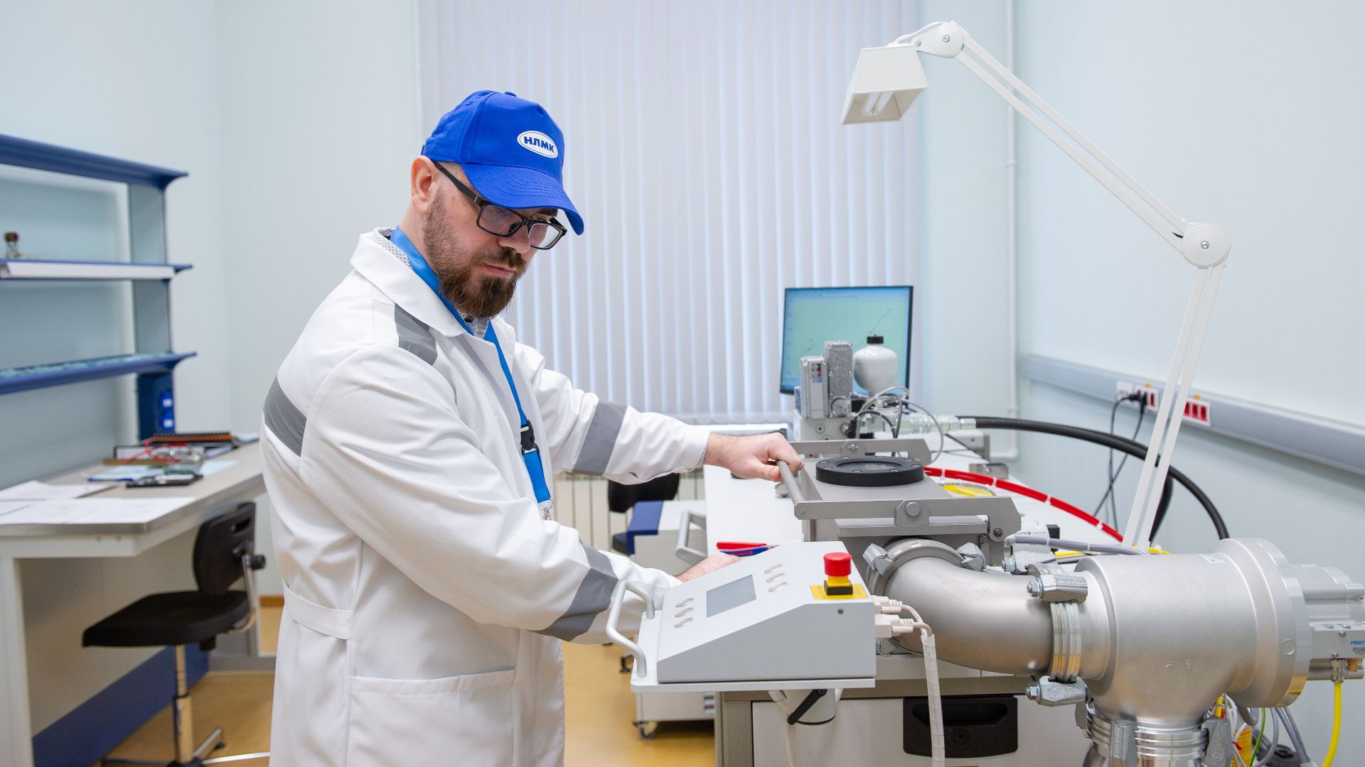 Lab technician in white coat operating advanced scientific equipment indoors