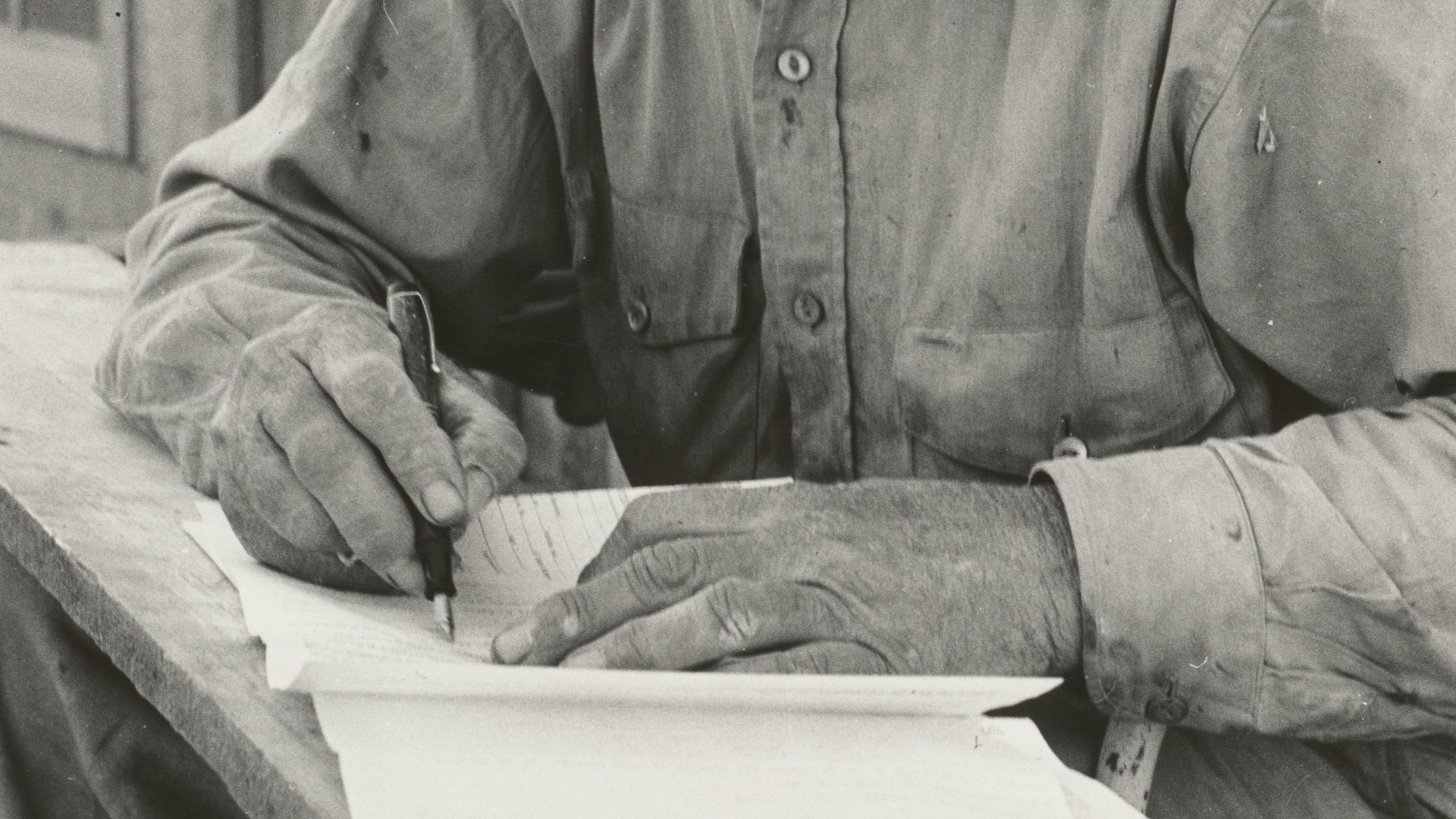 grayscale photography of man writing outdoors
