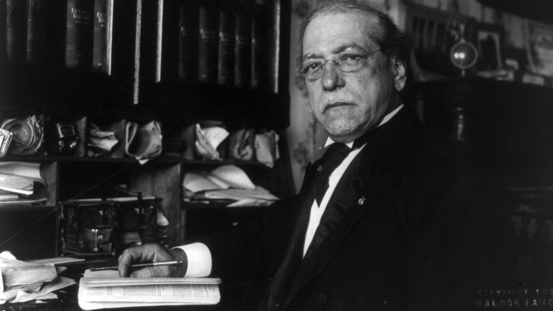 Samuel Gompers, half-length portrait, seated at desk, facing left
