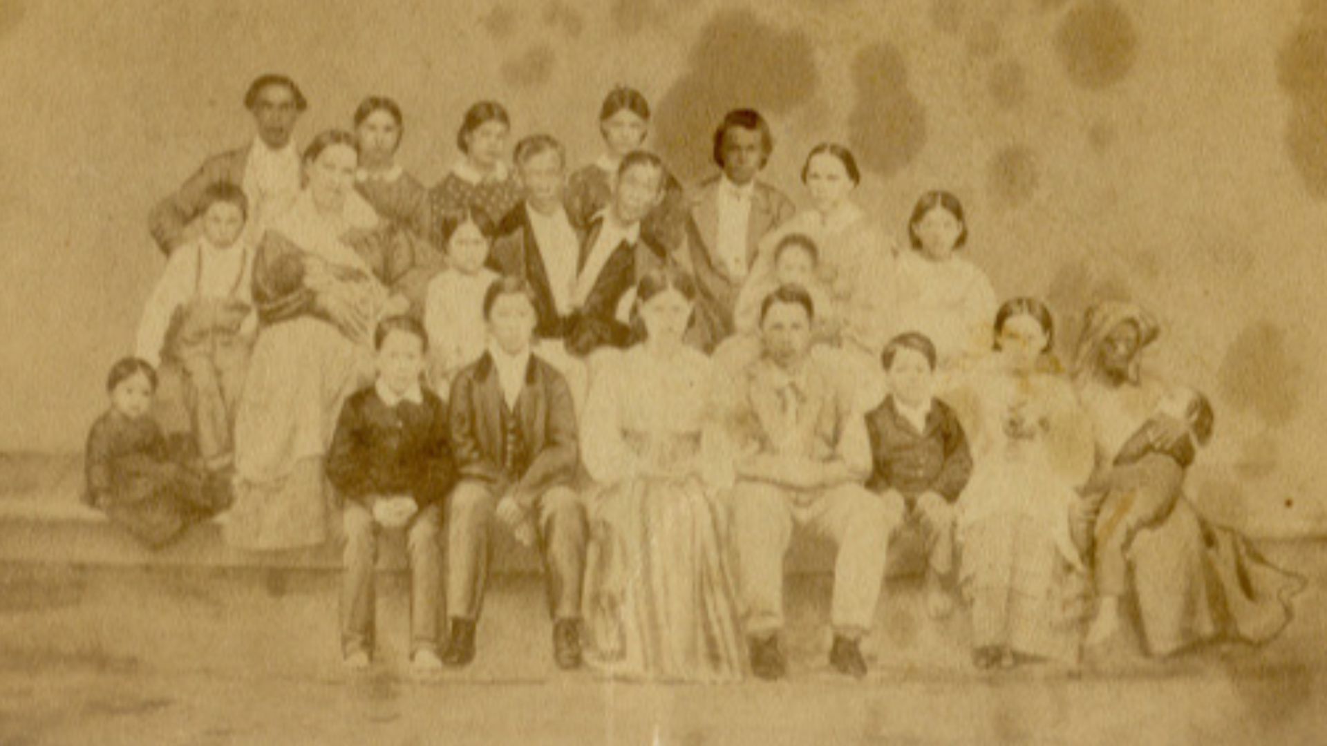 This family portrait from the 1860s shows Chang and Eng Bunker with their wives and 18 of their 22 children. It also includes Grace Gates, one of the 33 slaves on their plantation.