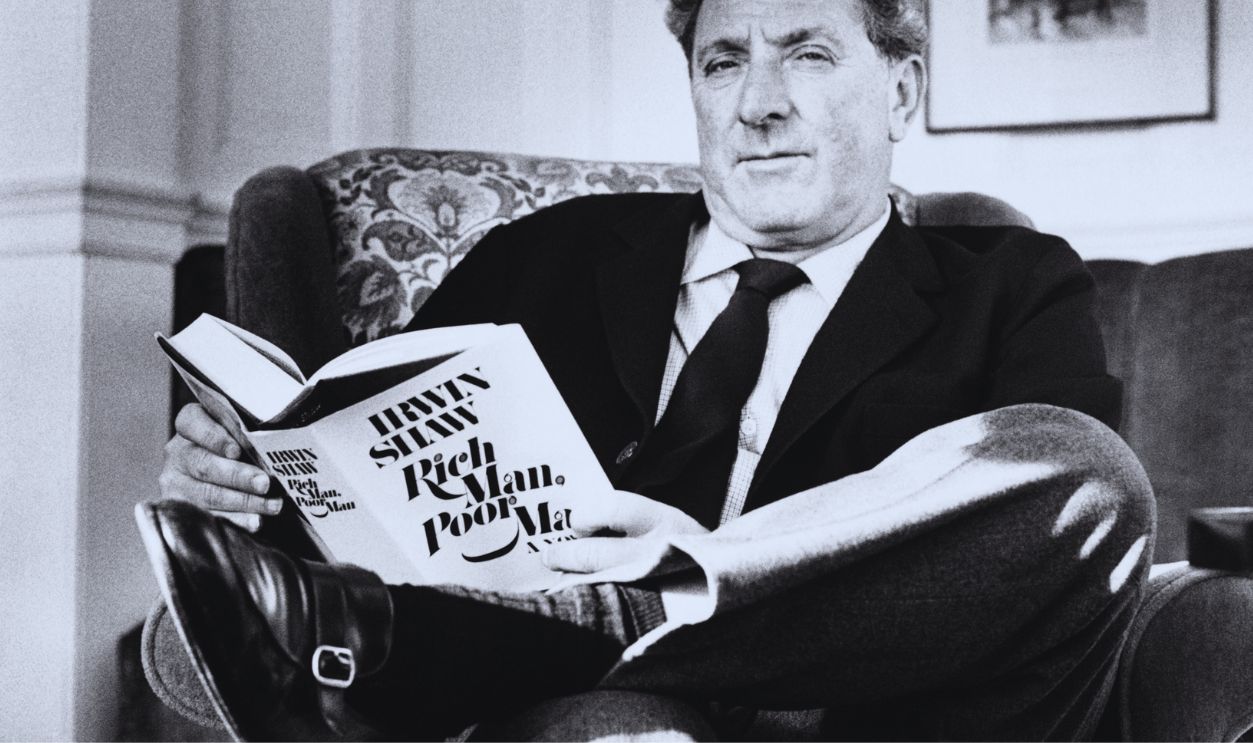 The American author Irwin Shaw, sits reading a copy of his own novel Rich man, poor man, 1970. He is in London for its launch.
