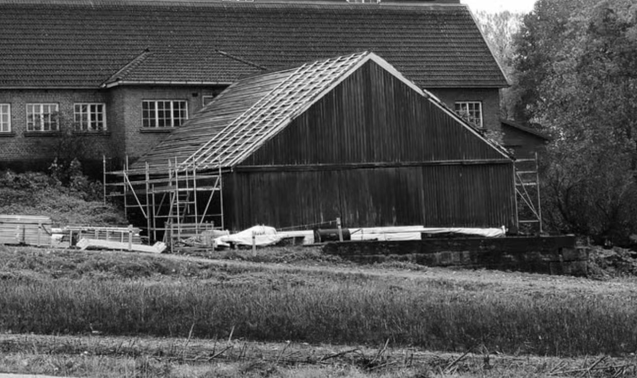 Black and white image of a rustic barn with trees in a serene setting