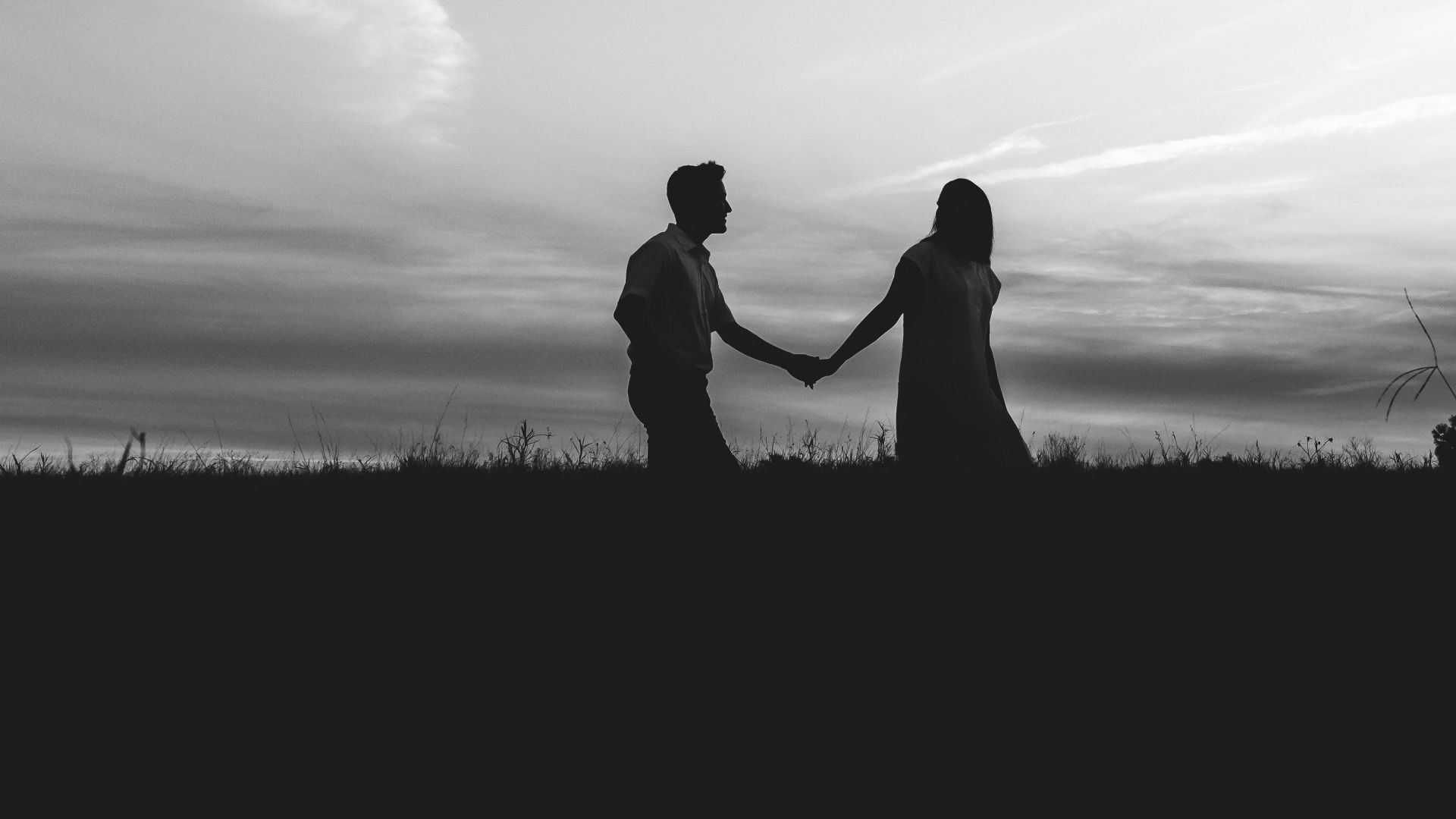 silhouette of man and woman kissing on grass field under cloudy sky during daytime
