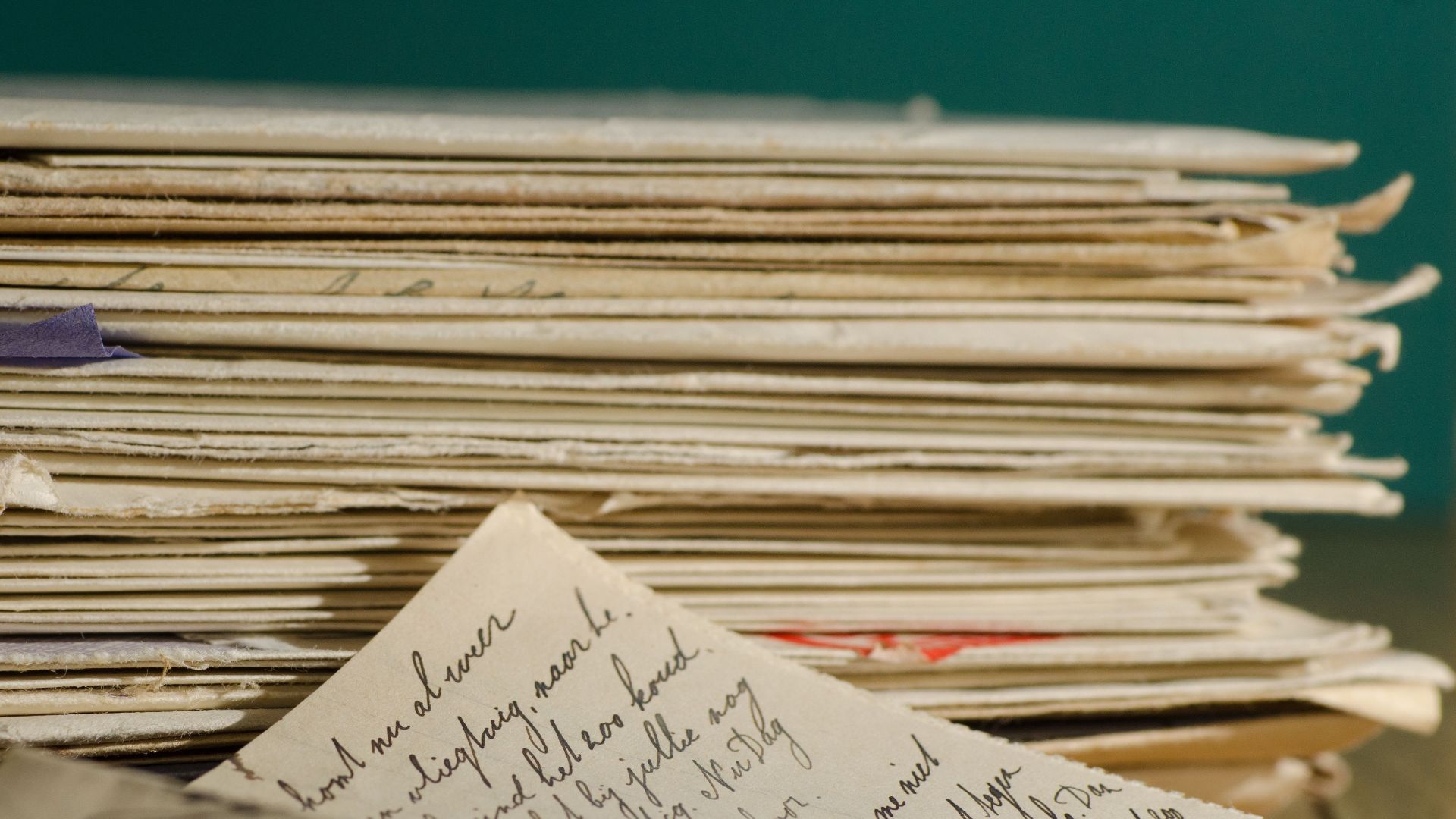 Close-up image of handwritten letters and papers stacked together, conveying a vintage feel.
