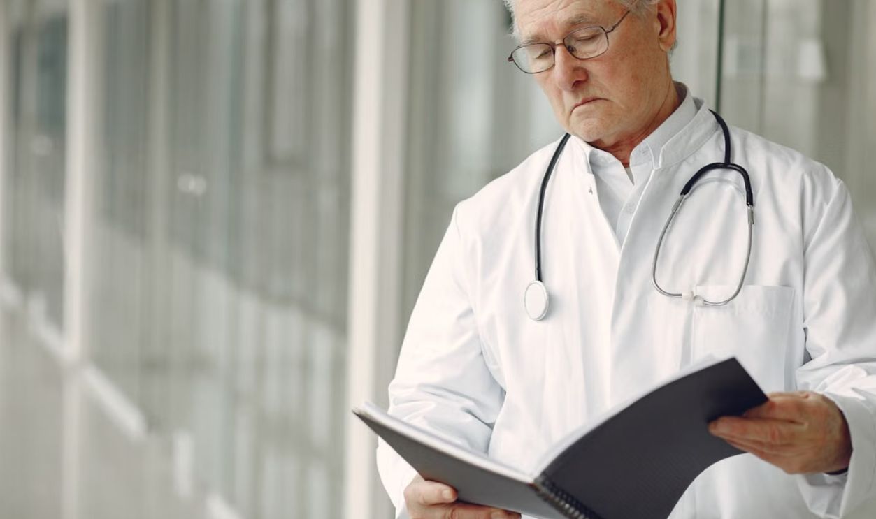 Elderly doctor with stethoscope attentively reading a medical report in a modern hospital setting