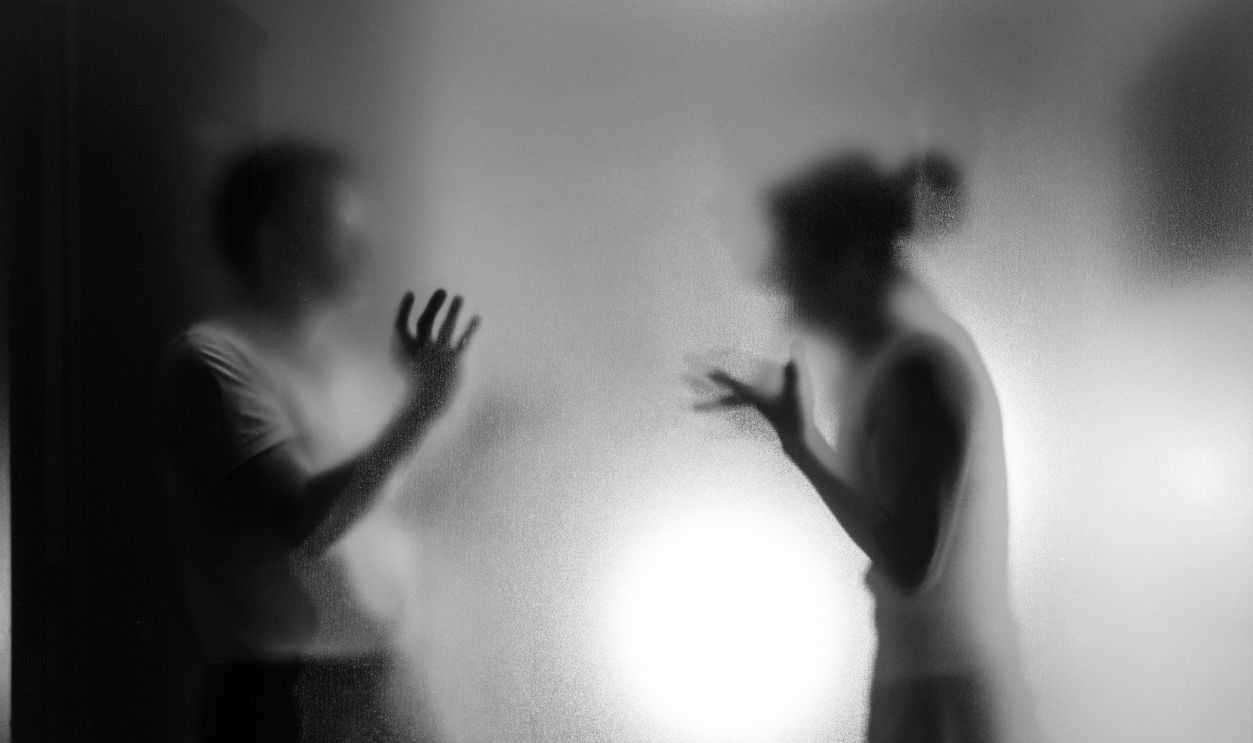 Couple arguing behind the frosted glass
