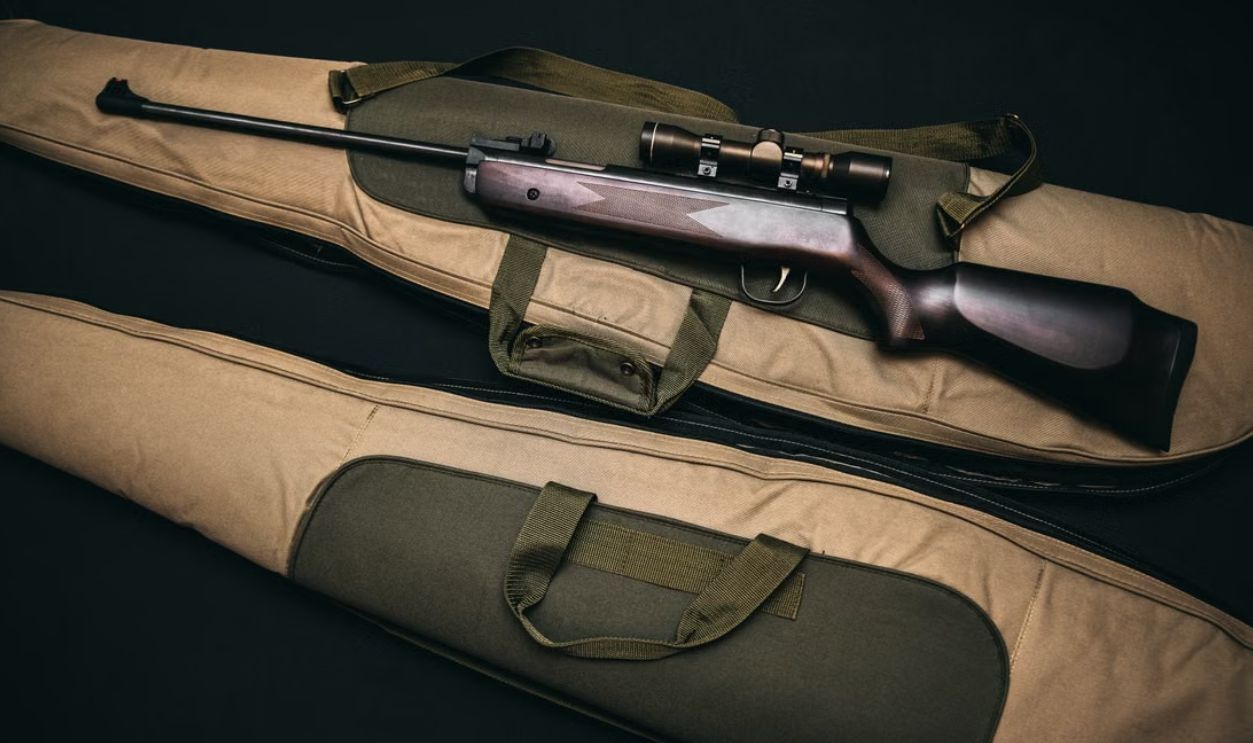 Close-up of a hunting rifle with a scope on a carrying bag, showcasing firearms and hunting gear