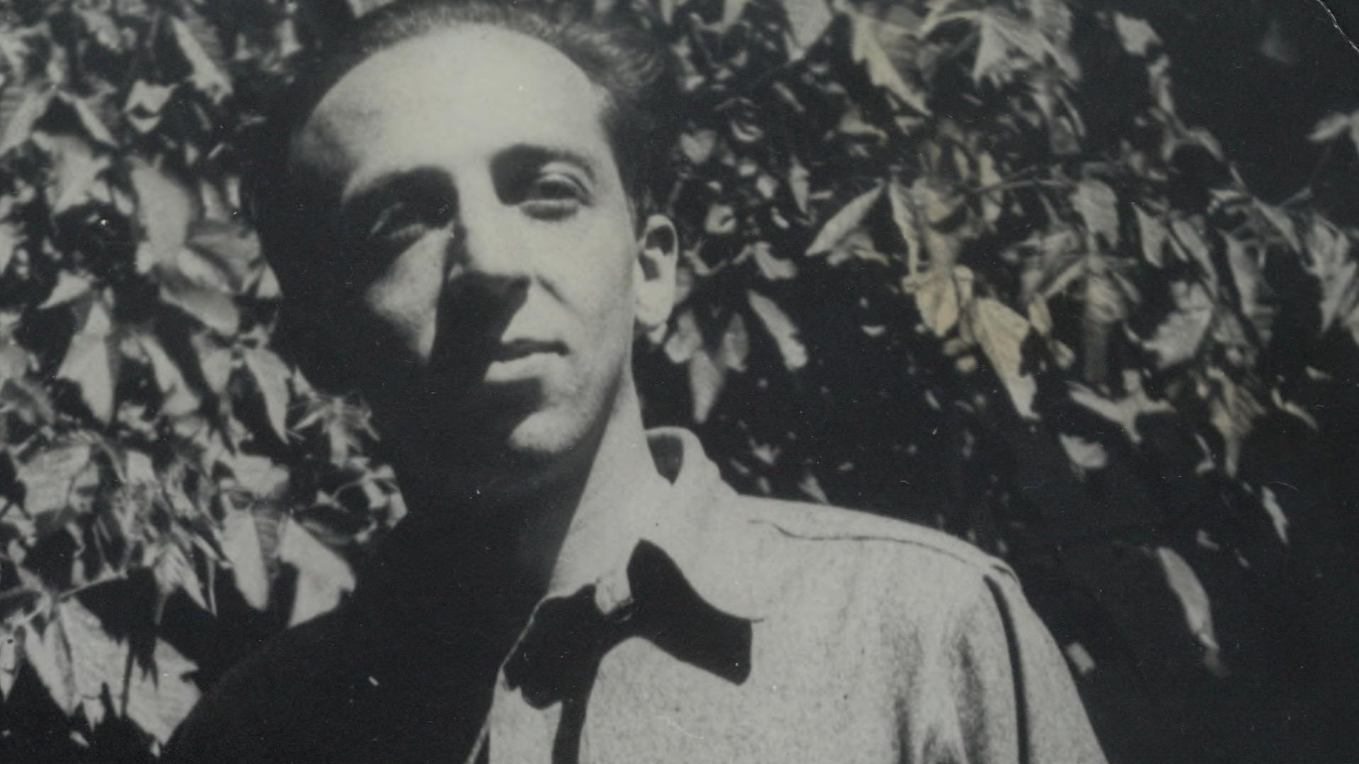 Aaron Copland standing in front of foliage in 1930