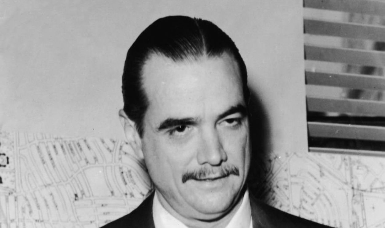 American industrialist, aviator, and film producer Howard Hughes (1905 - 1976) stands in front of a wall-mounted street map, mid 1946.