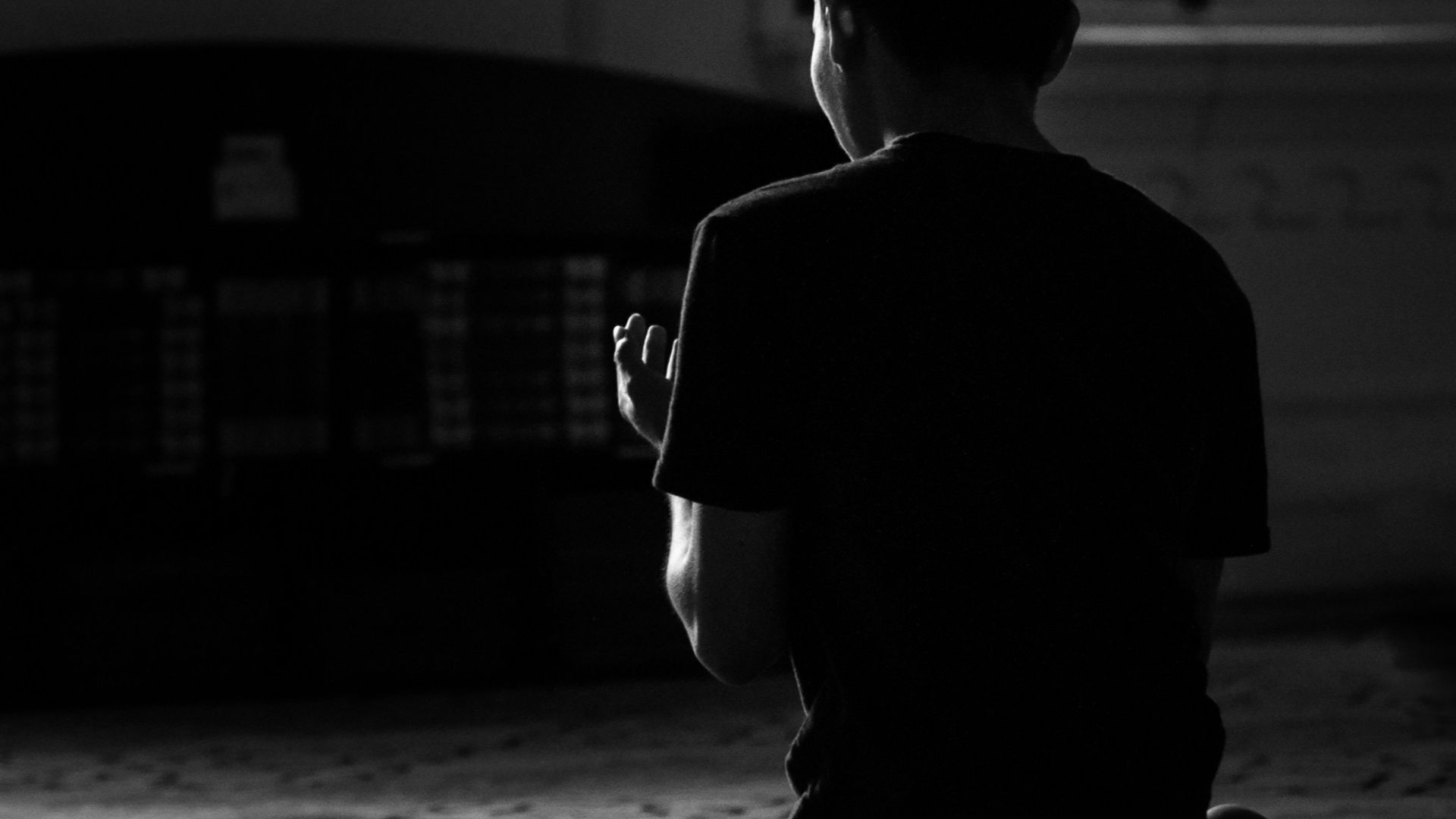 grayscale photo of man in black suit sitting on floor