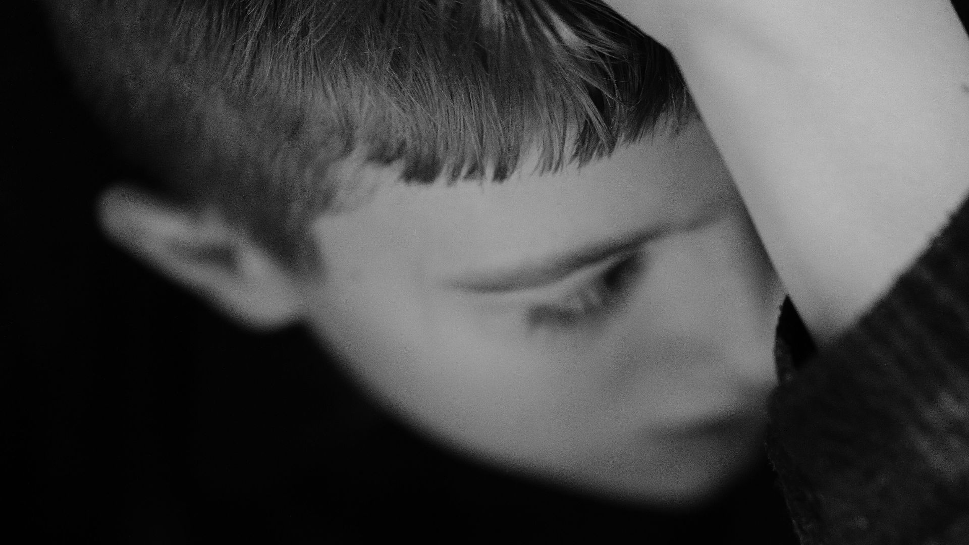 A boy gazes down with his hand on his head
