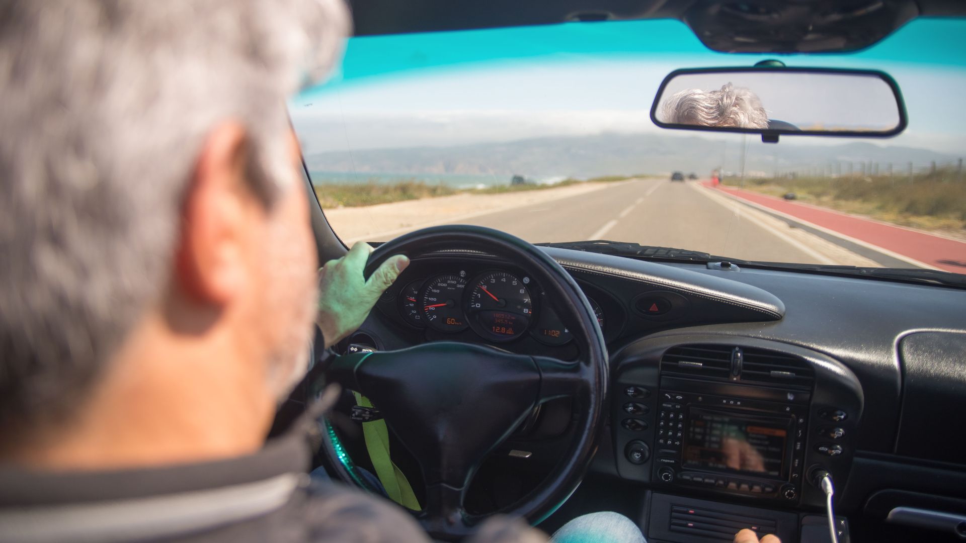 A person driving a car on a scenic highway in Portugal on a sunny day.