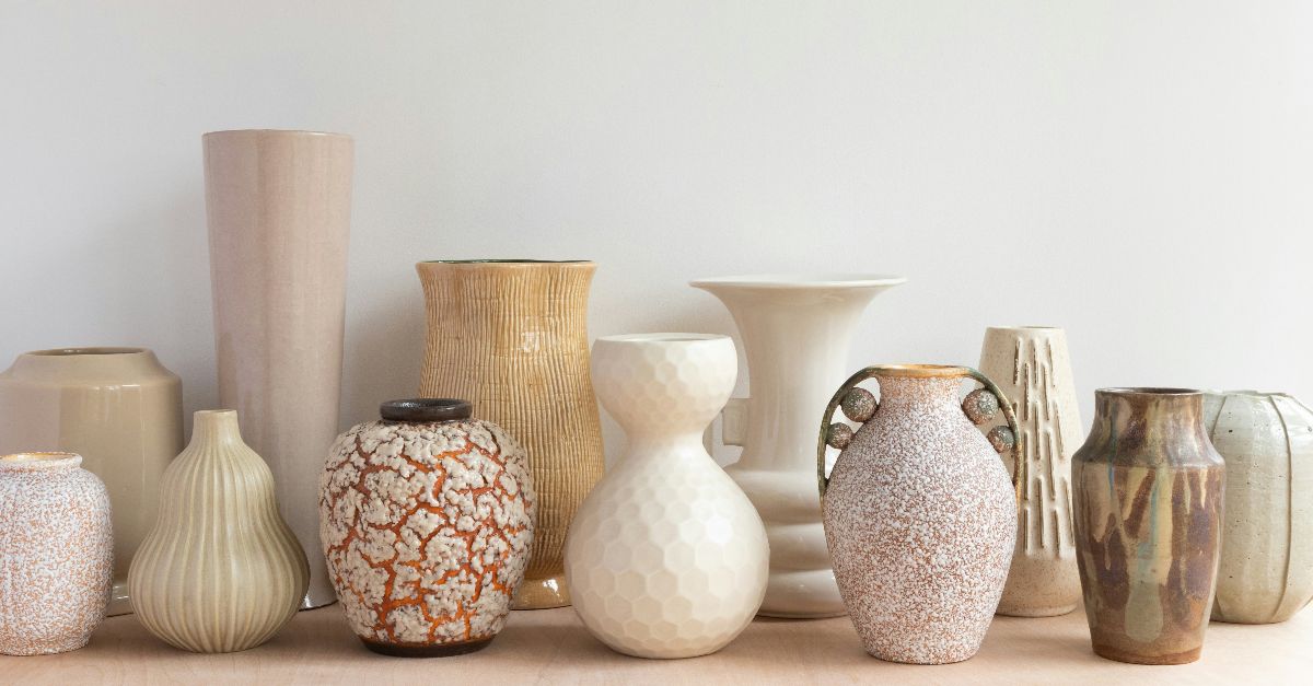 A collection of various ceramic vases in neutral tones on a wooden surface