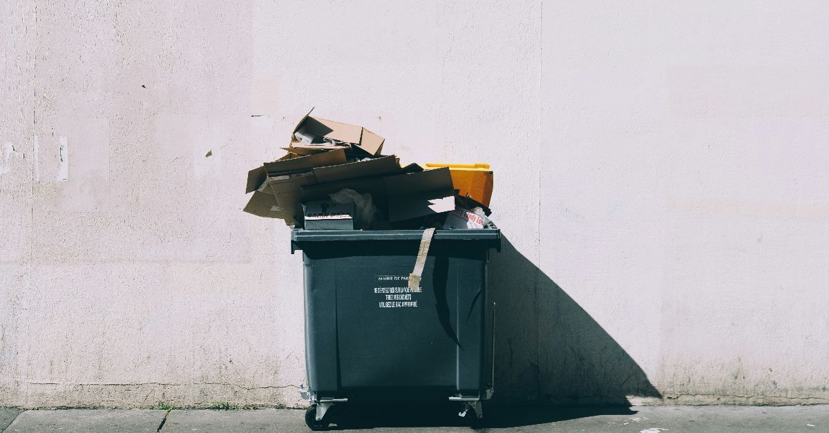 black plastic garbage bin with wheels beside wall