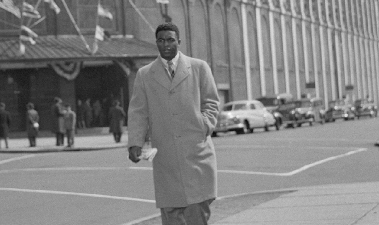 Brooklyn Dodgers baseball star Jackie Robinson walks on the sidewalk across the street from Ebbets Field, the Dodgers' home field. Robinson breaks the color barrier this season by becoming the first African American to play in the Major Leagues. April 16, 1947.