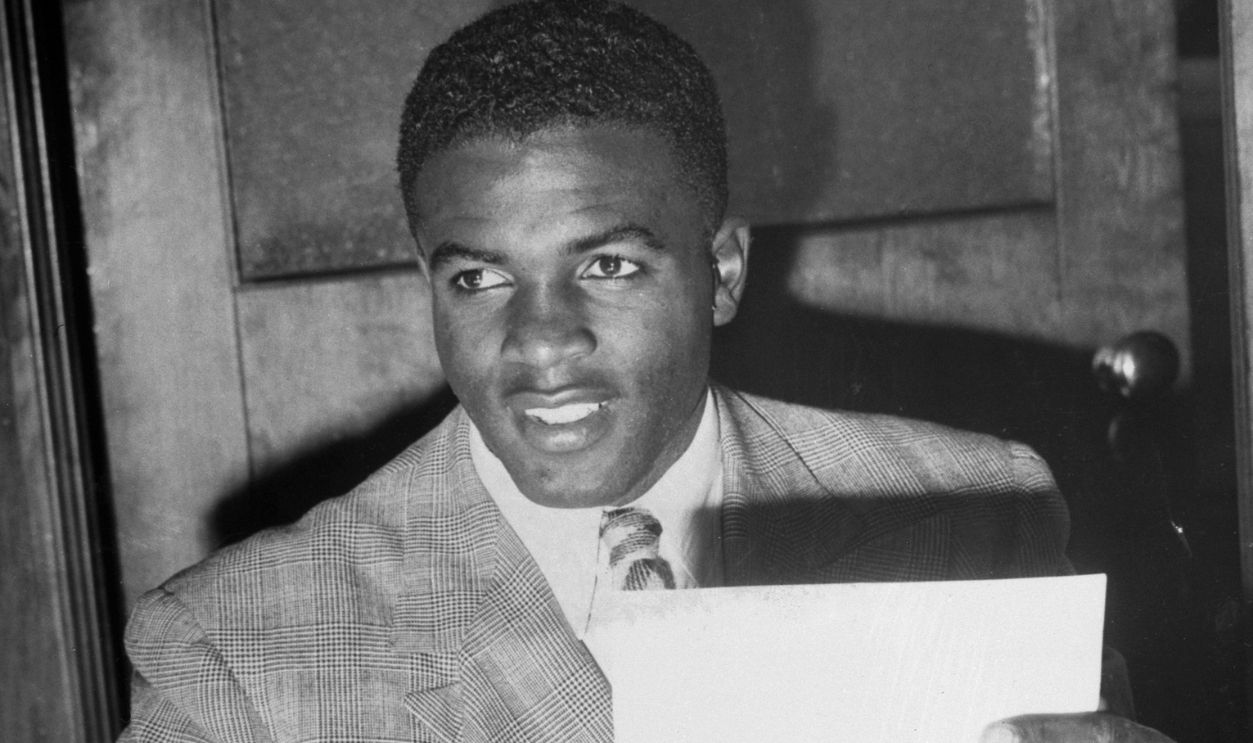 Jackie Robinson holds his contract to play with the Brooklyn Dodgers. Robinson spent 1946 with the Dodgers' minor league team in Montreal, becoming the first African American to play in organized white baseball.