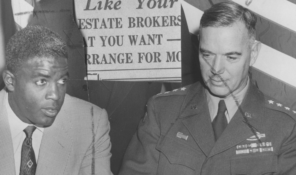 American baseball player Jackie Robinson (1919 - 1972) of the Brooklyn Dodgers with army officer at table, New York, New York, May 2, 1952