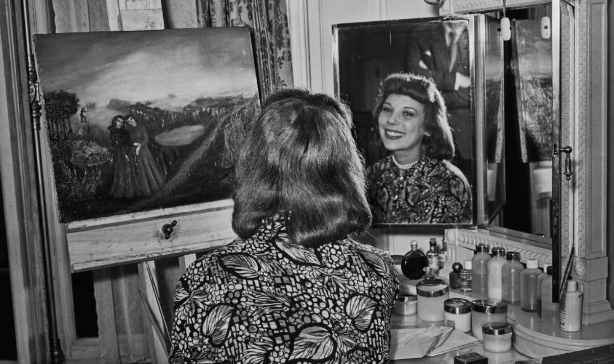 Dancer Tilly Losch smiles at her reflection in a dressing room mirror beside a painting, September 13th 1950. 