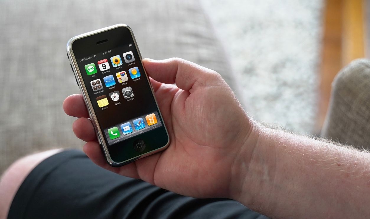 Male hand holding a 1st generation iPhone with the main display turned on. Originally released June 2007. January 21, 2021. San Francisco, CA.