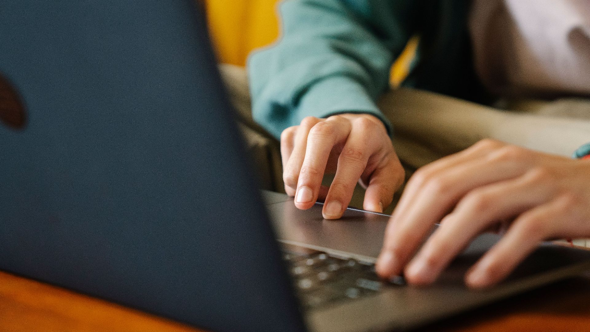 Crop unrecognizable distance employee surfing internet on netbook while working on project at desk in room