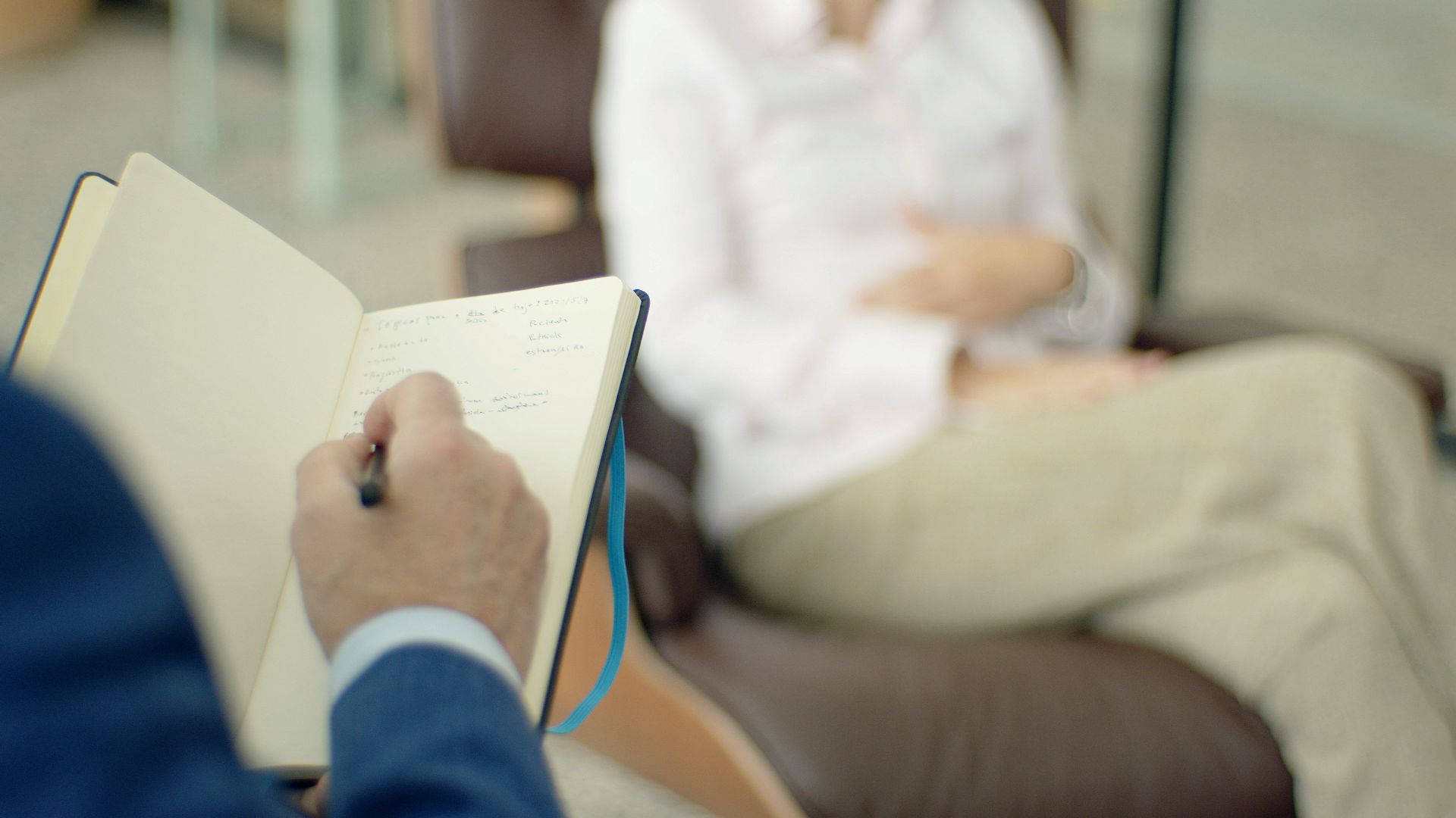 Therapist writing notes during a counseling session with a client.
