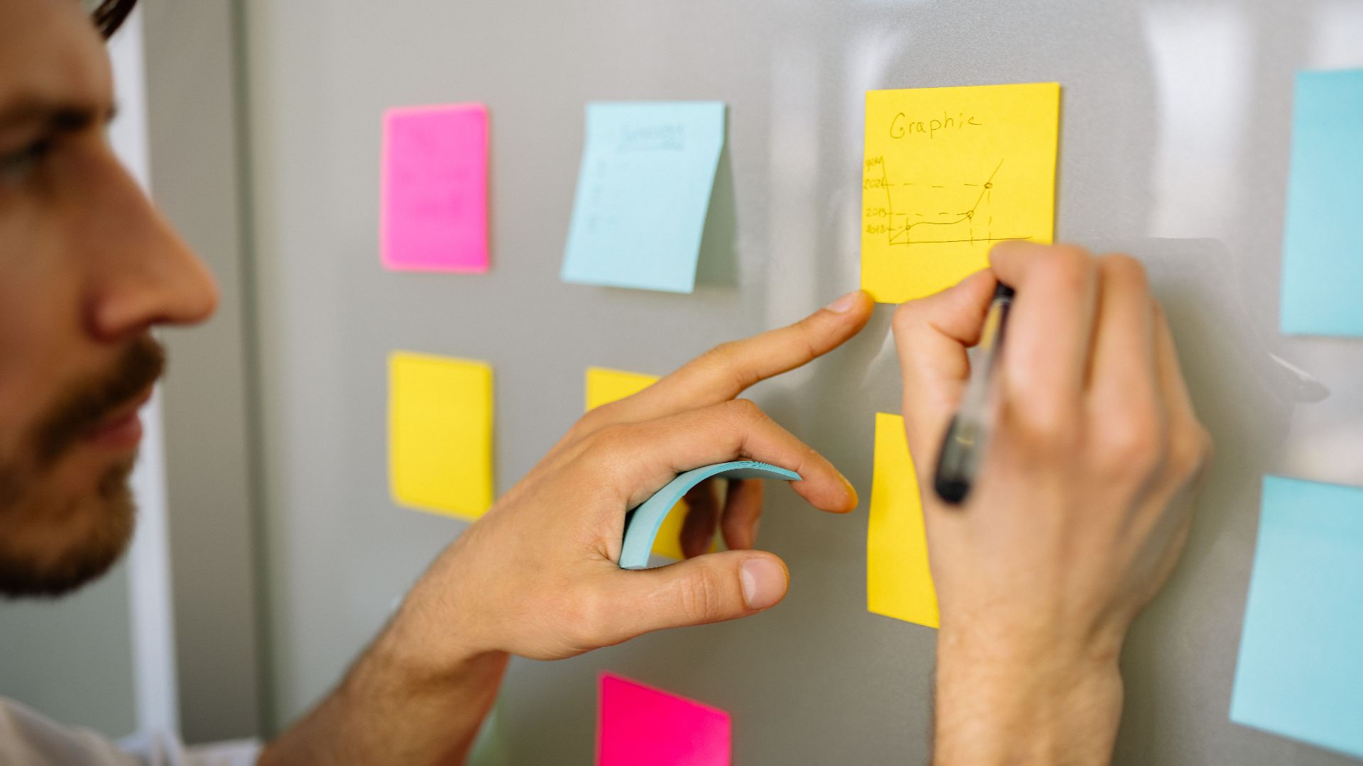 Focused businessman writing ideas on sticky notes for planning and organization.