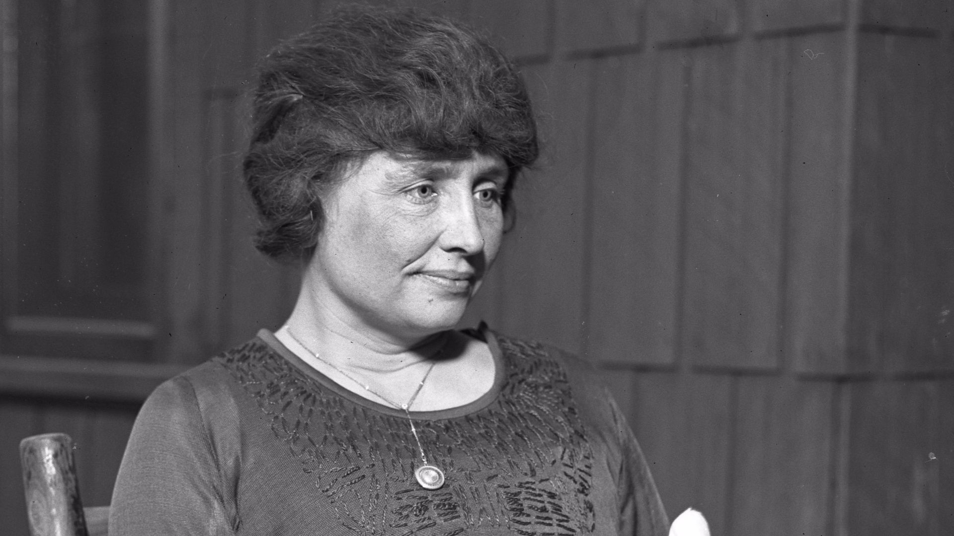 Helen Keller sitting holding a magnolia flower, circa 1920