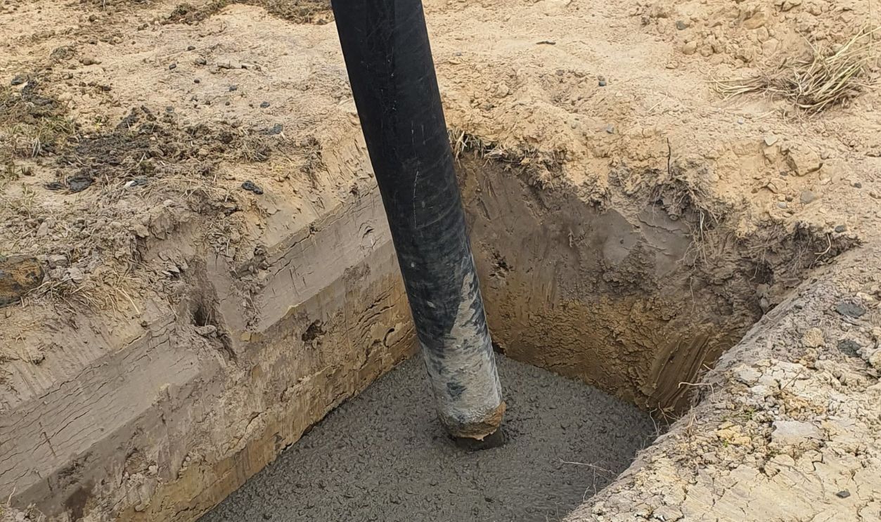 Worker using hose to pour concrete into foundation at site in Poland