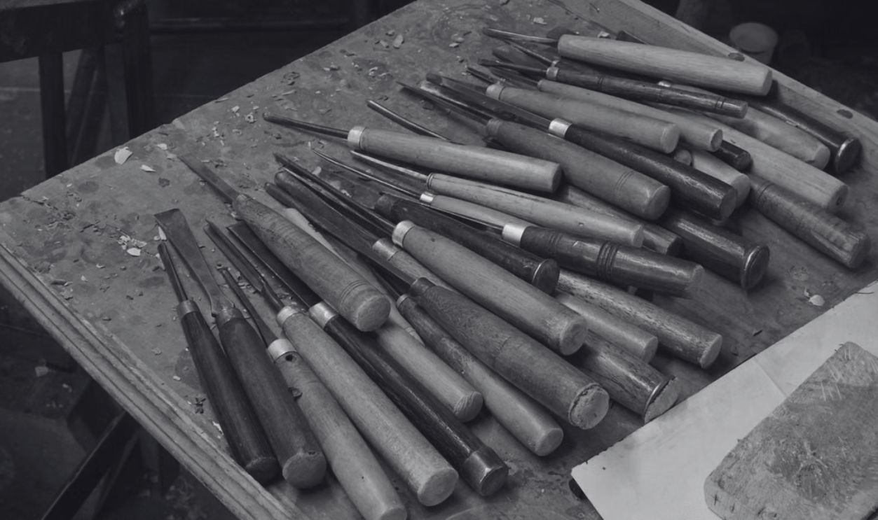 A variety of hand tools used for traditional woodturning and woodcraft on a workbench