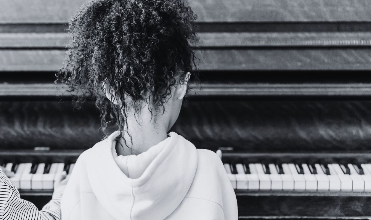 A boy and a girl practicing piano together indoors, fostering friendship