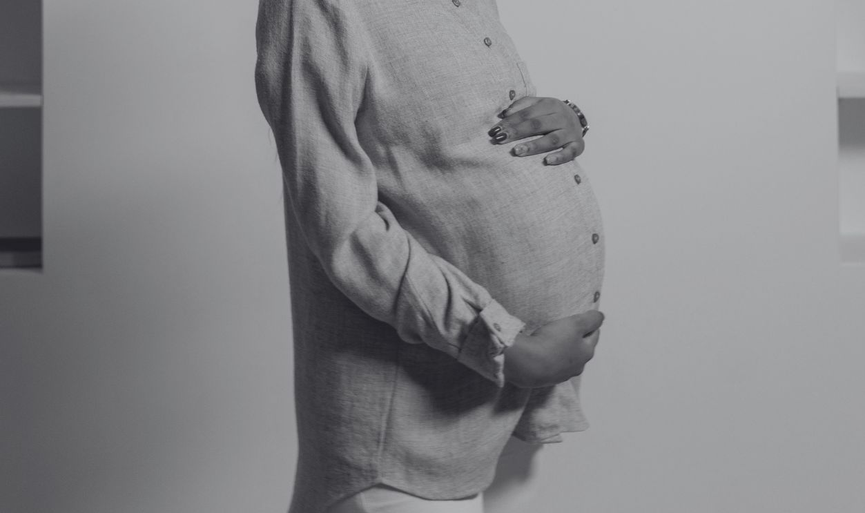 African-American woman lovingly looks at her baby bump