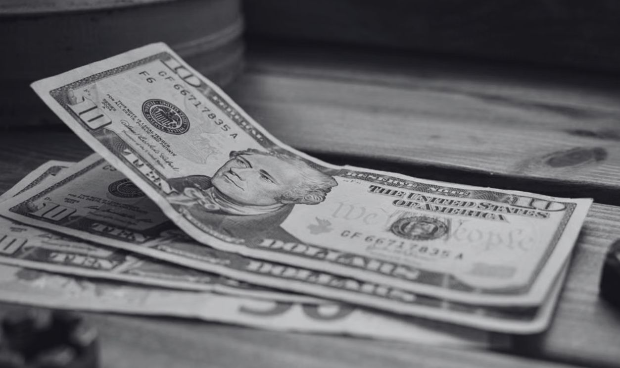 A stack of US dollar bills on a rustic wooden table close-up view